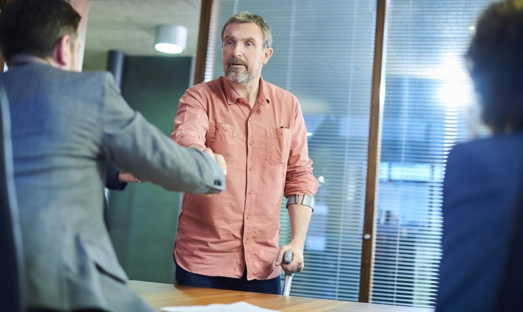 A personal injury lawyer and his injured client shake heads over a desk, most likely in agreement.